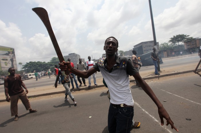 Anti-Gbagbo protester holds a machete near a roadblock and burning tyres in the Abobo area of Abidjan