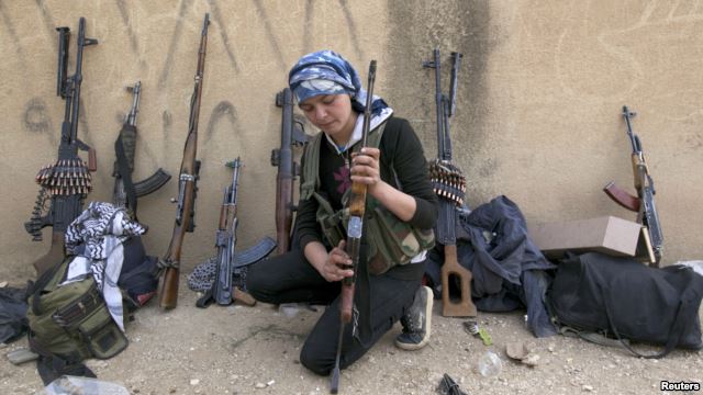 A Kurdish female fighter from Kurdish People's Protection Units [YPG] checks her weapon near Ras al-Ain, in the province of Hasakah, after capturing it from Islamist rebels, November 6, 2013.